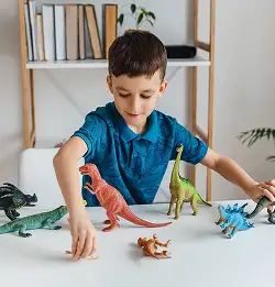 Clid playing with plastic colorful dinosurs
