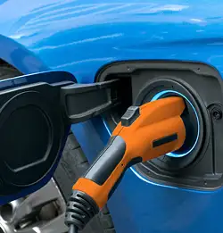 Bright orange handle for gas pump inserted in bright blue car