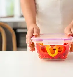 person sealing a clear food container