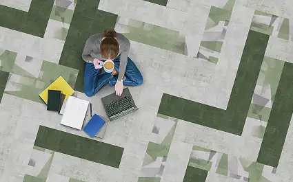 person sitting on LVT floor with a cup of coffee and computer