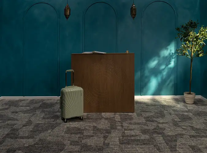Teal wall with reception desk and roller bag on Quite Statement carpet tile