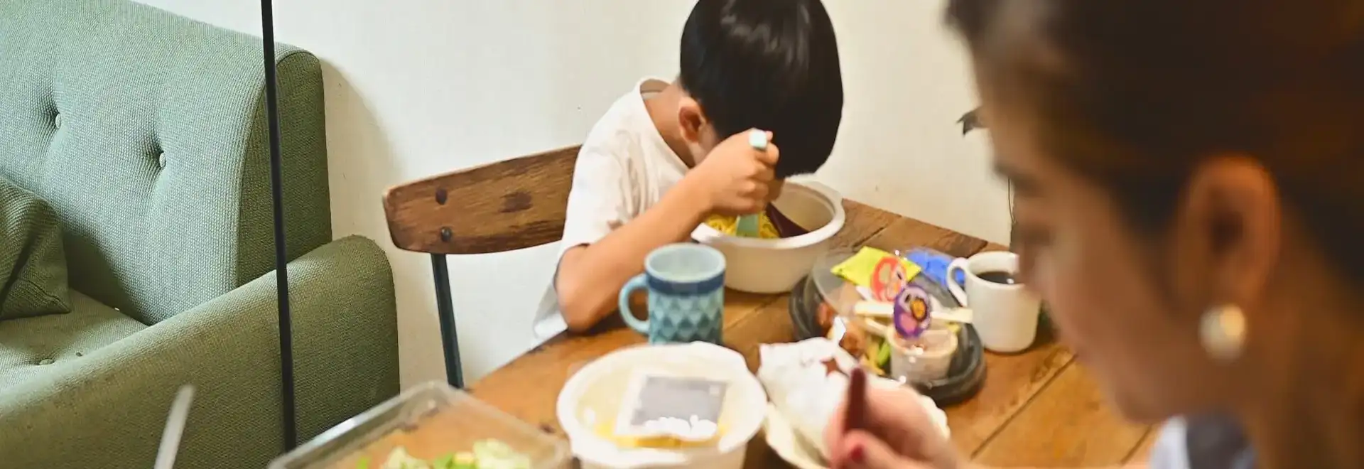 Child eatting out of disposable bowl while a mother watches