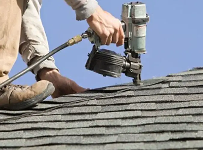 close shot of a person nailing shingles onto a residential roof