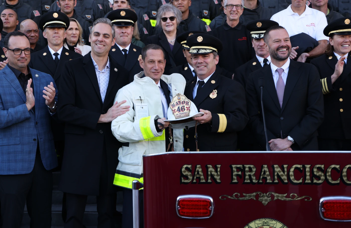 San Francisco Firefighter in firefighter turnout gear holding helmet with mayor