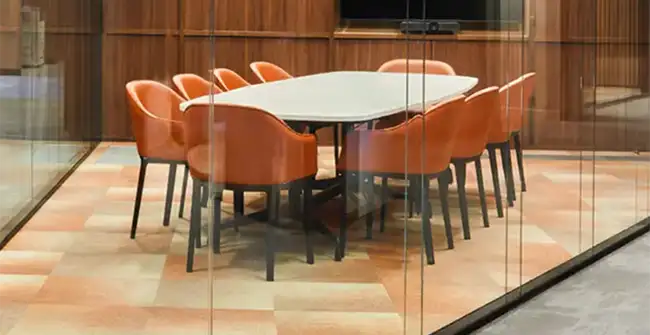 glass conference room with orange chairs on a soft tonal carpet tile transitioning between soft yellow and organge