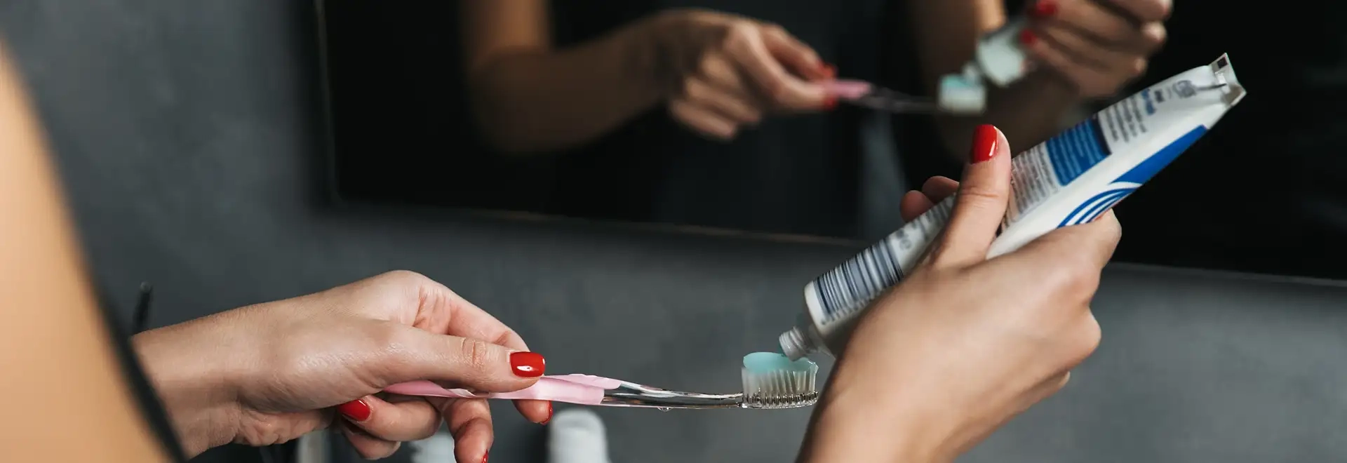 close up shot of person putting toothpaste on toothbrush