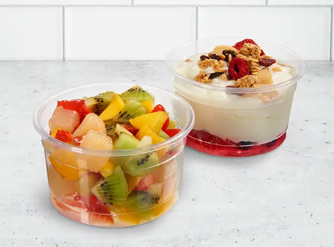 clear food containers with colorful fruits and a desert
