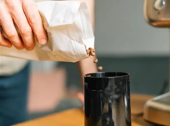close up of person pouring coffee beans from packaging into container