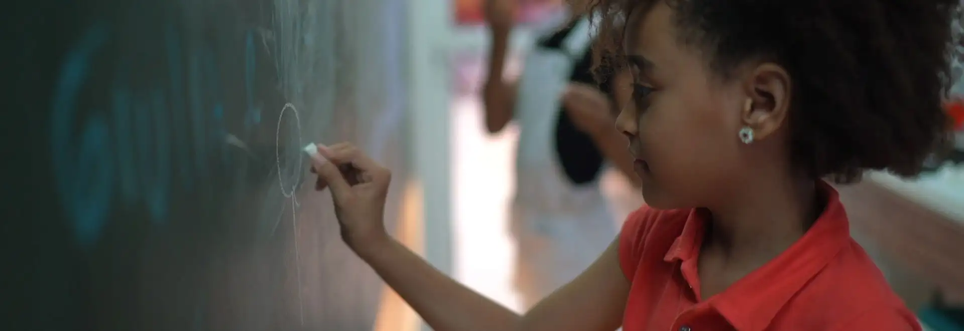 young student writing on chalk board