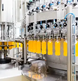 bottle filling machine loaded with bottles filled with orange drink