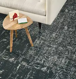 close up of sofa corner and wooden side table on gray textured carpet tile flooring
