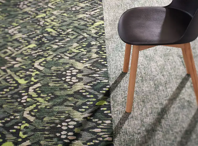 close up of chair leg on green geometric carpet tile with gray transition