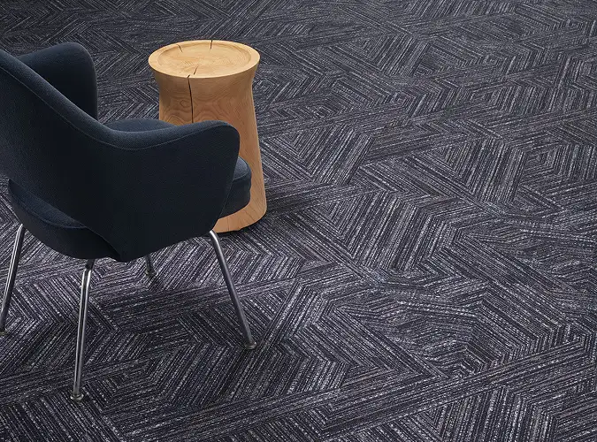 modern chair with a turned wooden side table on a geometric blue and white carpet installation