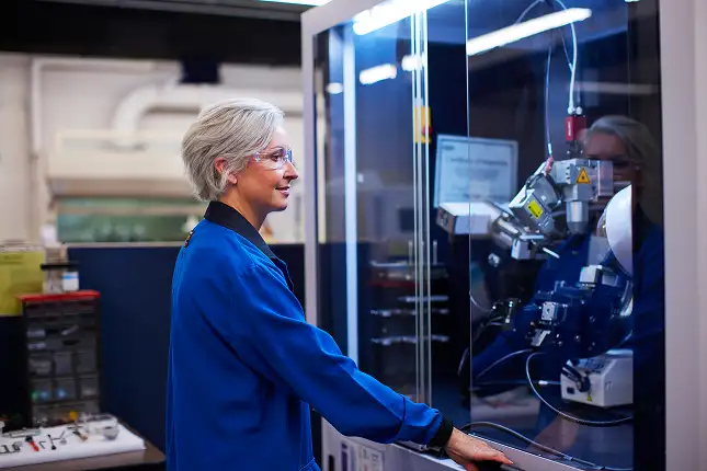 person wearing safety gear working on a testing machine