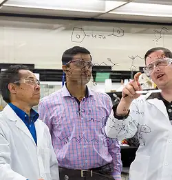 scientitist in discussion using a glass board 