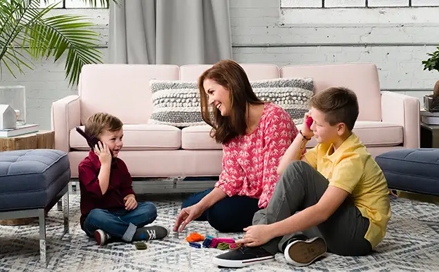 Family sitting on the floor in a living room with Milliken interior fabric covered sofa