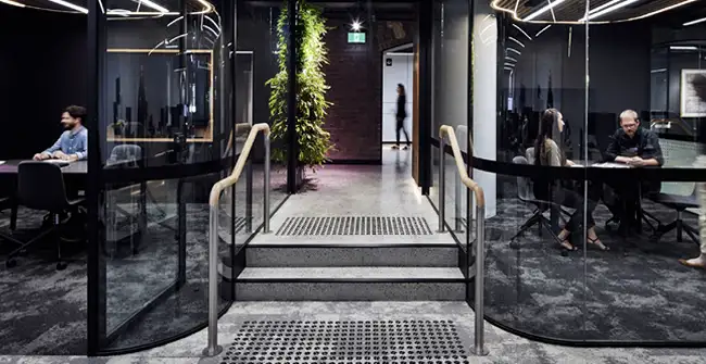 hallway with curved glass walled conference spaces with people meeting