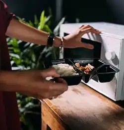 Person putting food in frozen packaging into the microwave