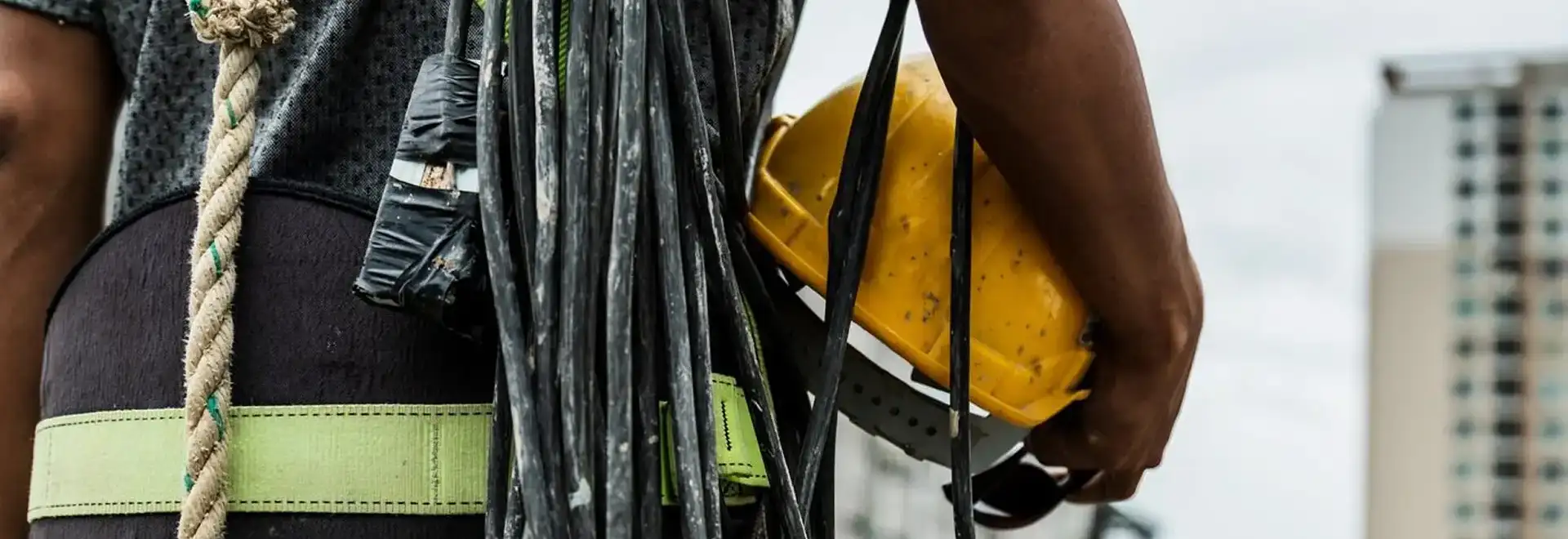 close up of a cable managment worker from behind with hard hat and cable over the shoulder