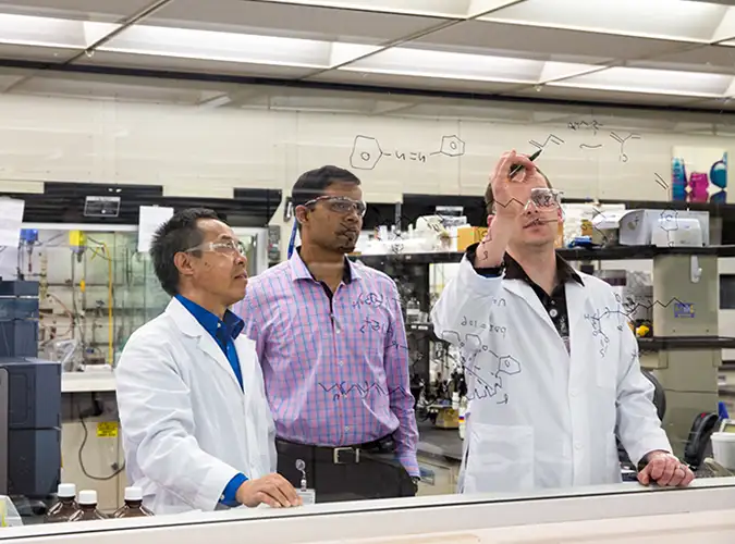 Associates problem solving on glass whiteboard