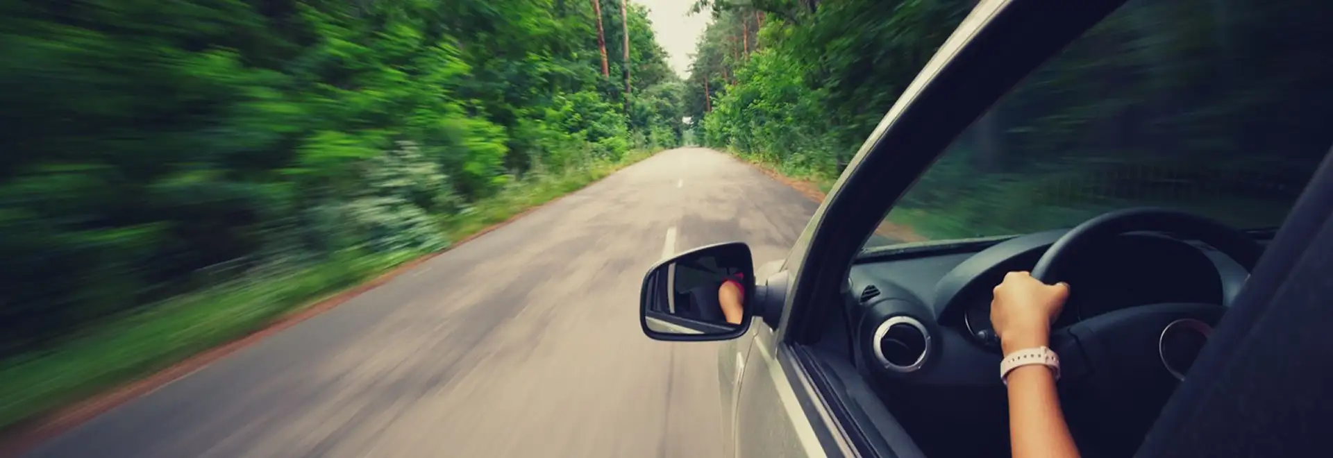 view from outside of the car of a road with greenery