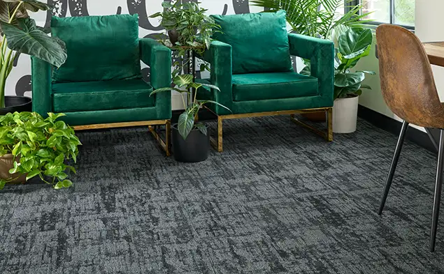 Two green chairs on gray carpet tile form the Echo Field collection