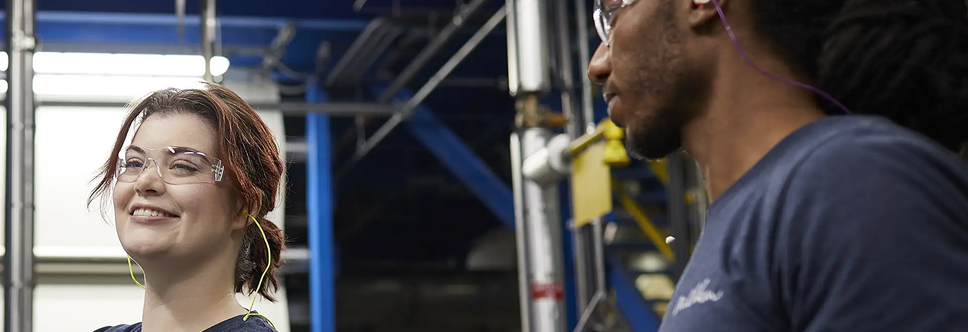 smiling woman with a marker in front of whiteboard wearing safety glasses