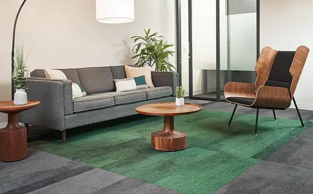 seating area with wood coffe table and plants on green inset in gray field of Sound of Color capet tile