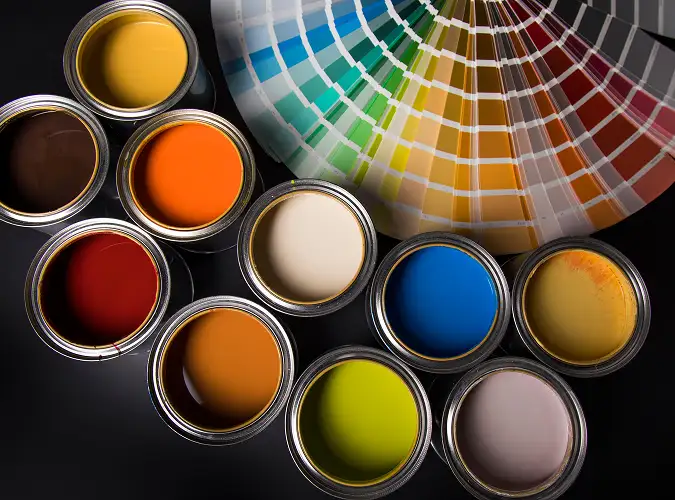 opened paint cans with colorful paints and a fan of colors on a paper color selector
