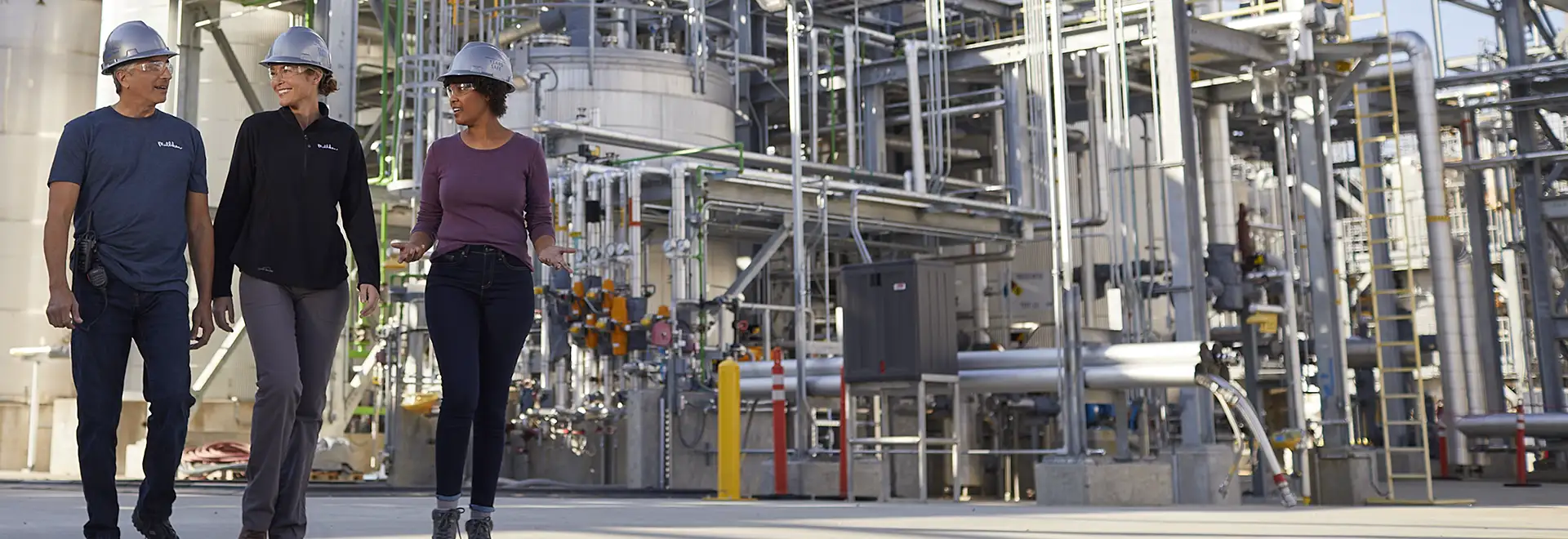 Group of people with safety gear in front of chemical tanks and equipment