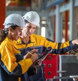 two workers in safety gear looking at a clipboard