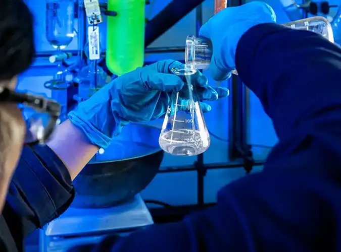 Milliken associate in the lab with a beaker containing fluid