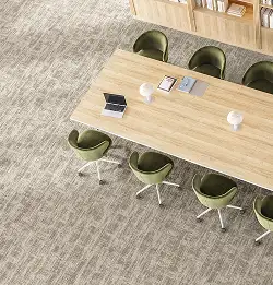 light wood meeting table surrounded by green chairs on tan textural carpet tiles