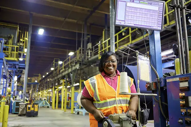 person on manufacturing plant floor wearing yellow safety vest