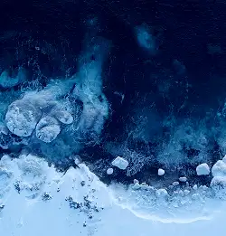 aerial view of very blue water and a white icy bank