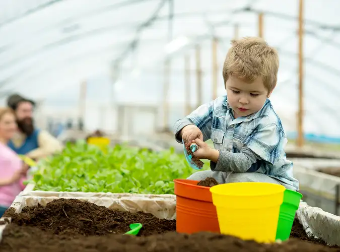 Child digging soil with 3 colorful buckets