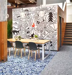 Seating area with tall chairs and table on blue geometric carpet inset into a field of gray textured carpet tiles