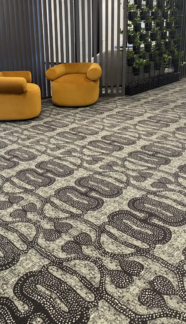 picture of workspace with Reconiliation Through Design carpet and two orange chairs