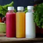 three clear bottles with brighly colored juices