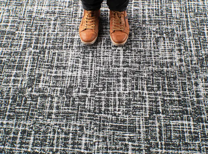 close up of brown shoes standing on black and white SDN carpet tile