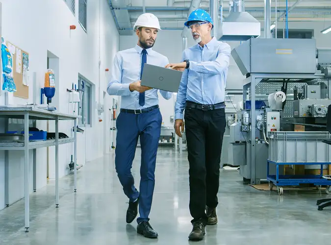 Two manufacturing professionals reviewing a change management framework in a factory setting