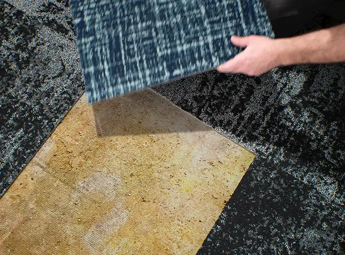 person placing carpet tile on floor