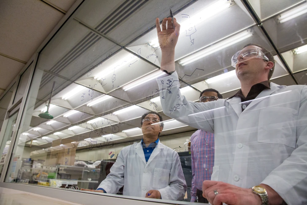 Scientists writing on glass wall