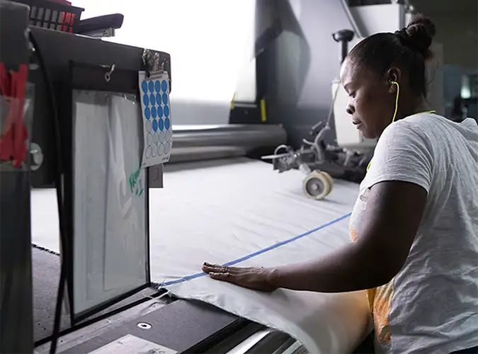 Associate inspecting fabric in lighted booth