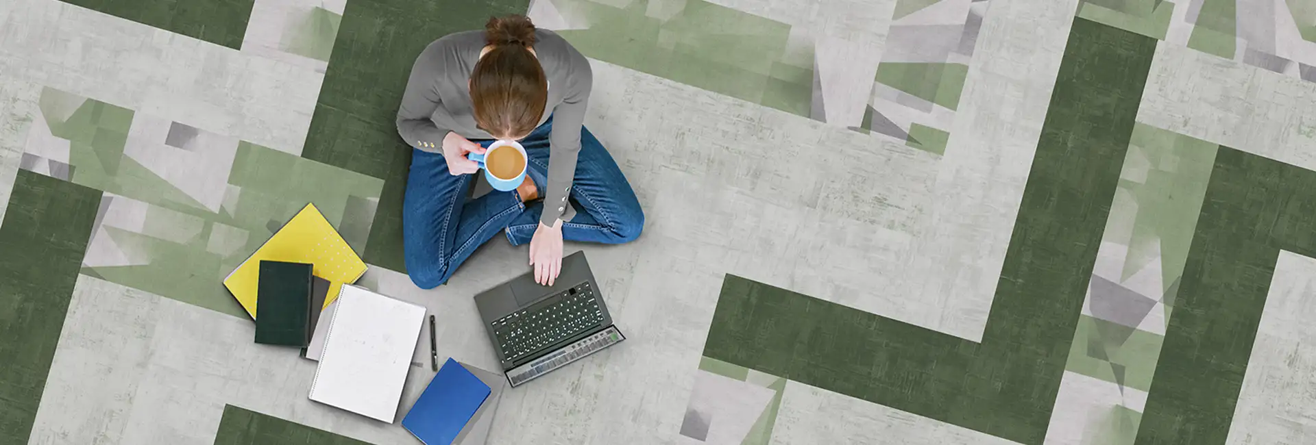 person sitting on LVT floor with a cup of coffee and computer