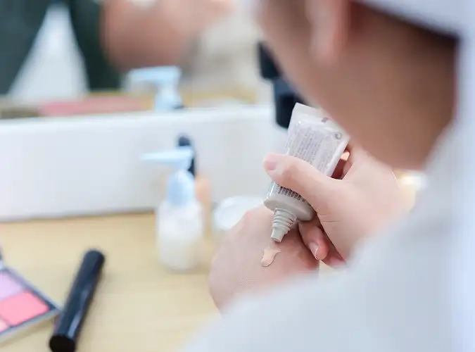 close up of person with a tube of makeup with some on hand