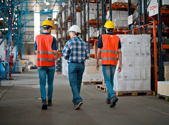 Gorup of assocaites wearing safety gear walking in warehouse area
