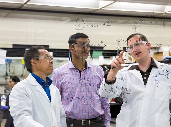 group of assocaiates problem solving on a clear board
