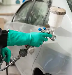 person spray painting a car