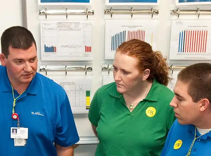 Group of people in discussion in front of a board with charts and graphs